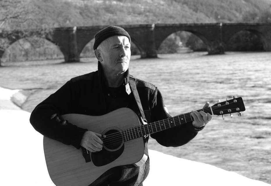 Fraser Nimmo plays a Martin guitar next to a river